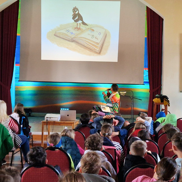 Kinder während einer interaktiven Bücherlesung mit projizierten Bildern an der Wand.