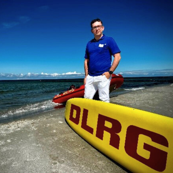 Johannes Vogel an der Ostsee, im Vordergrund gut sichtbar der DLRG-Schriftzug.