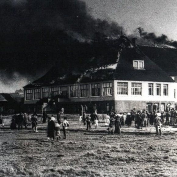 Historisches Foto des brennenden Ambronenhauses auf Amrum im Jahr 1925 – Flammen und Rauch steigen vom reetgedeckten Dach auf.